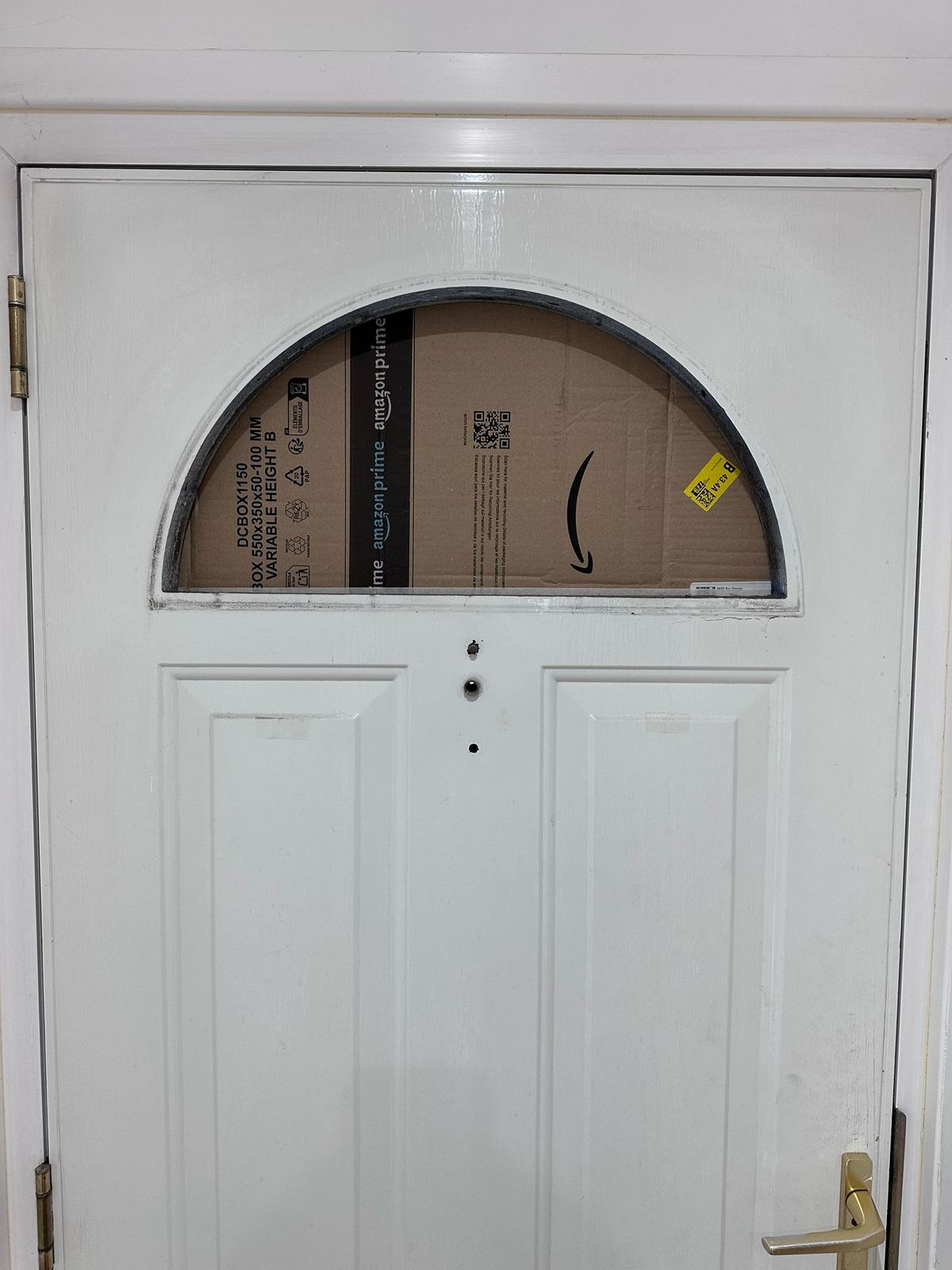 Broken door fanlight temporarily covered with cardboard — before board-up by LT Lockworks
